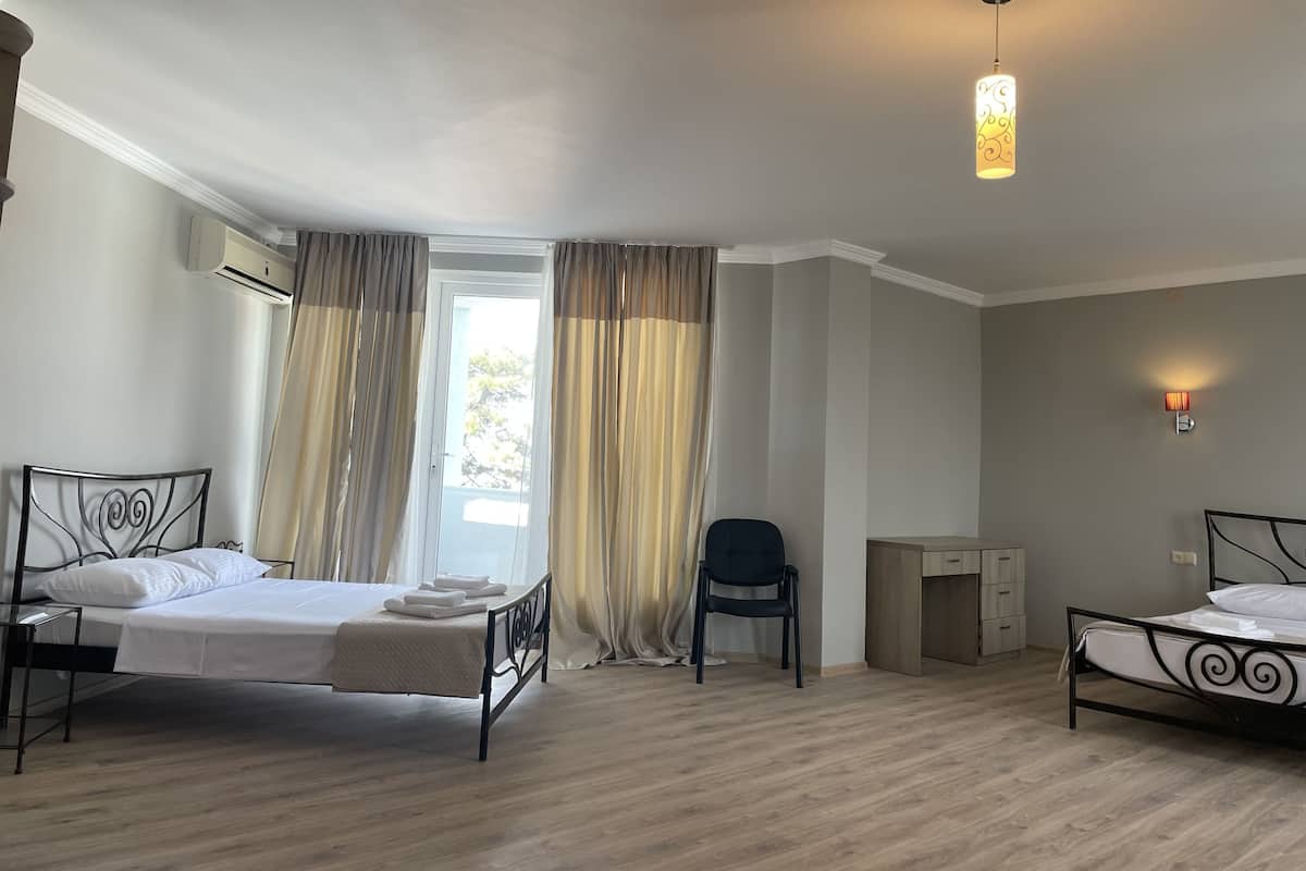 A bedroom with two beds, a desk, a chair, and a window with curtains.