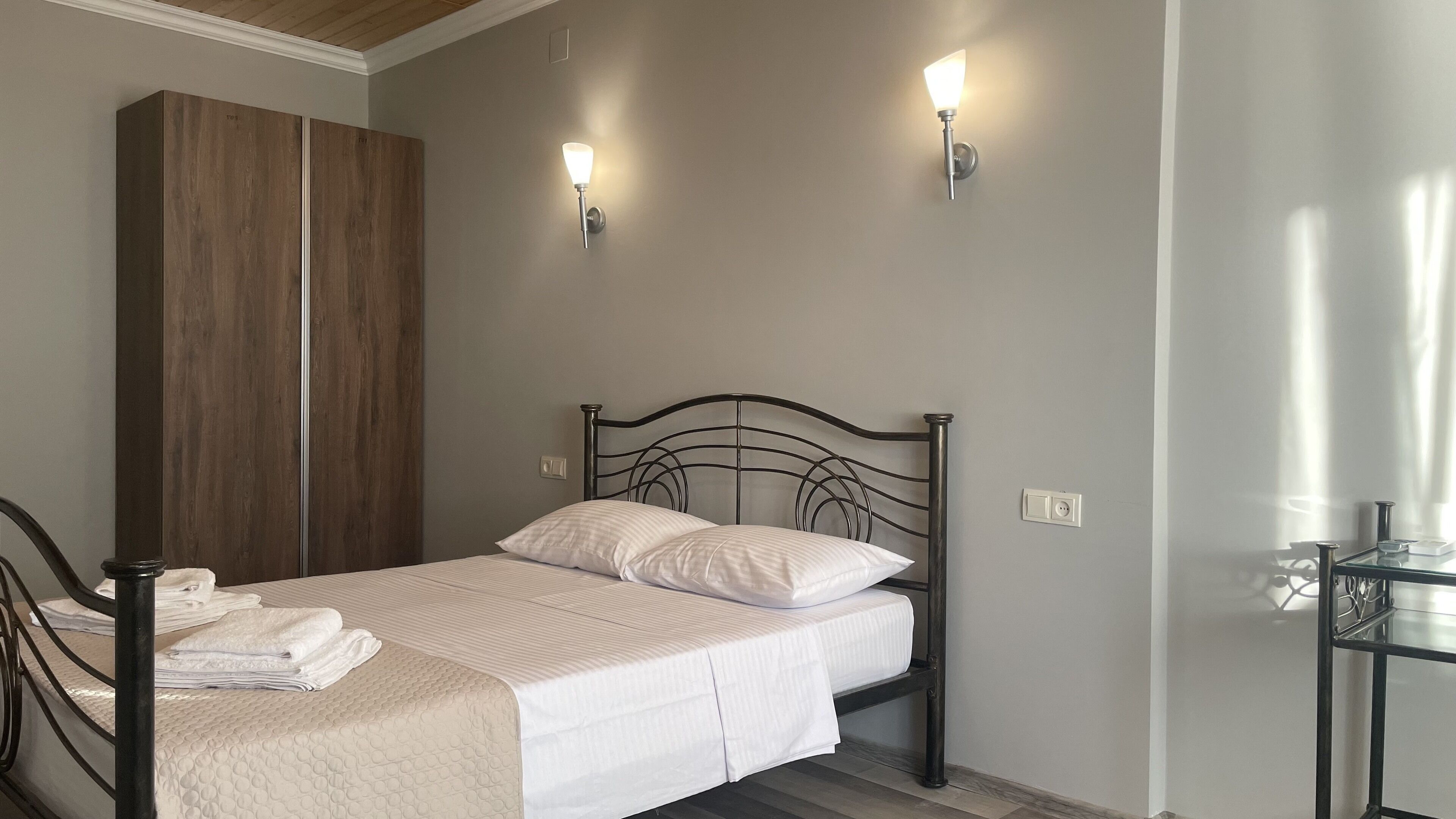 A bedroom with a bed, a wardrobe, and two wall-mounted lights.