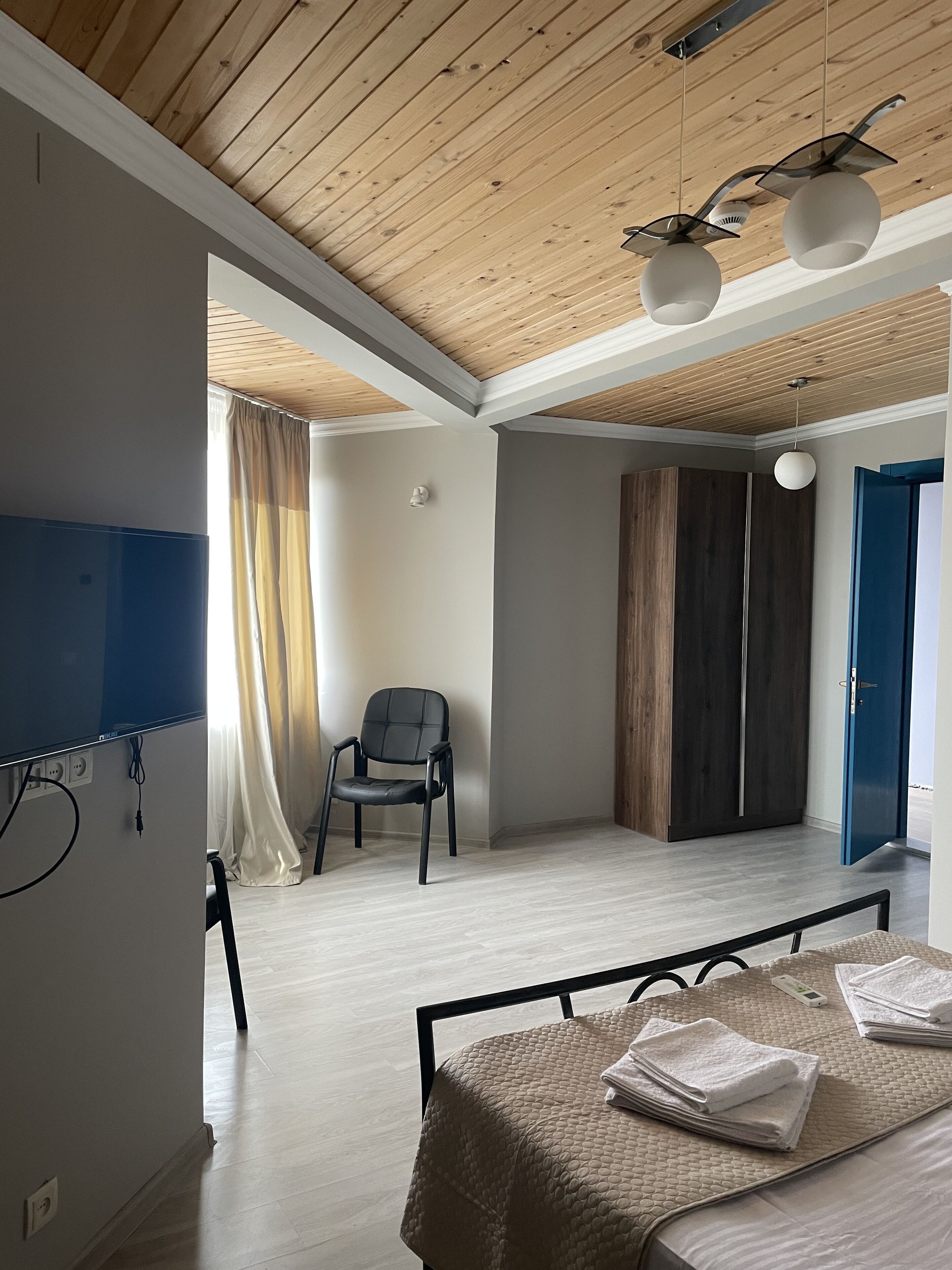 Una habitación con cama, una silla, un armario y televisor.