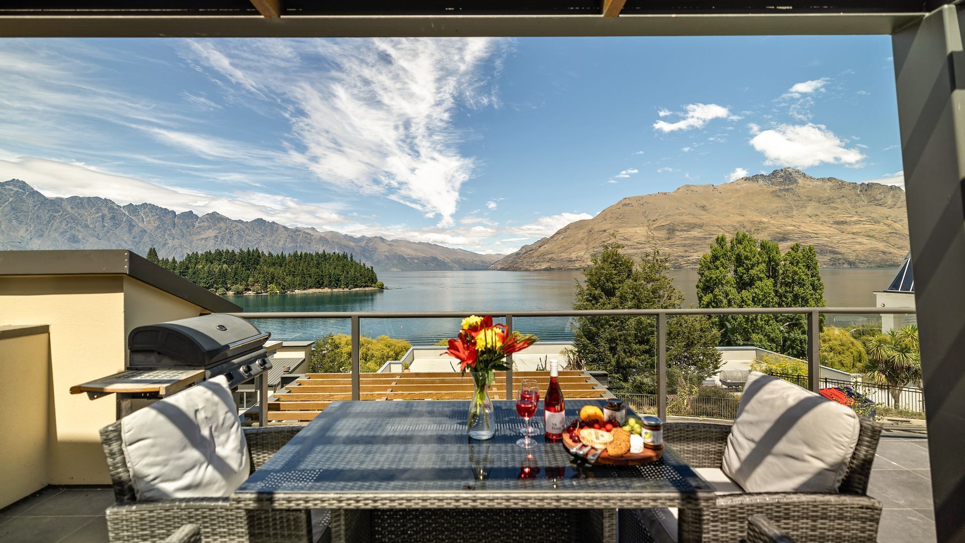 Un balcón con una mesa lista para comer, con vistas a un lago y montañas.