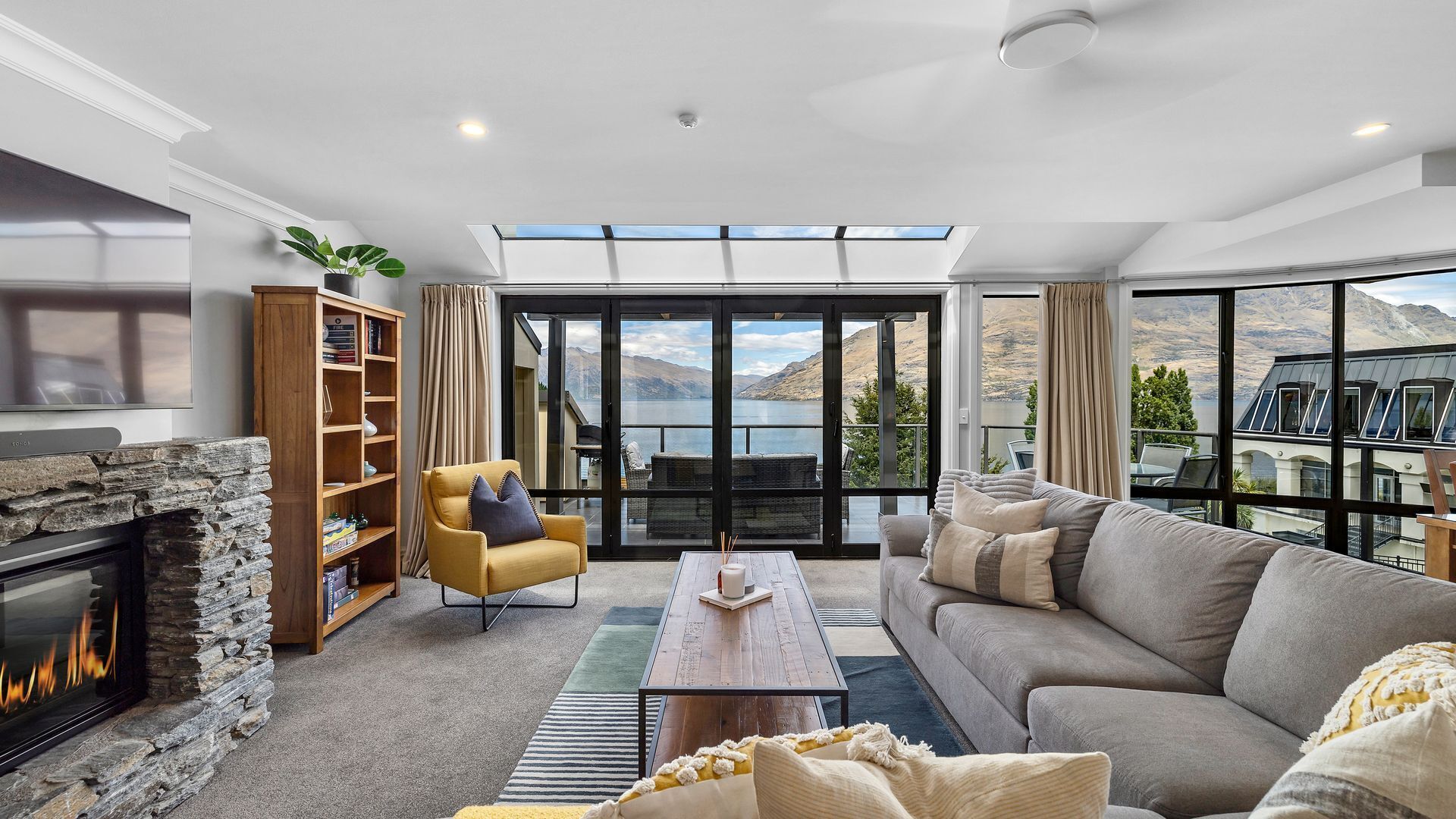 A modern living room with a stone fireplace, a sofa, a coffee table, and a bookshelf.