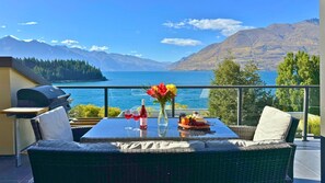 Een balkon met een eettafel, met uitzicht op een meer en bergen.