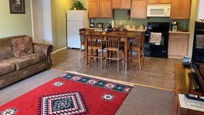 Un espacio habitable compacto con kitchenette, comedor y sofá.