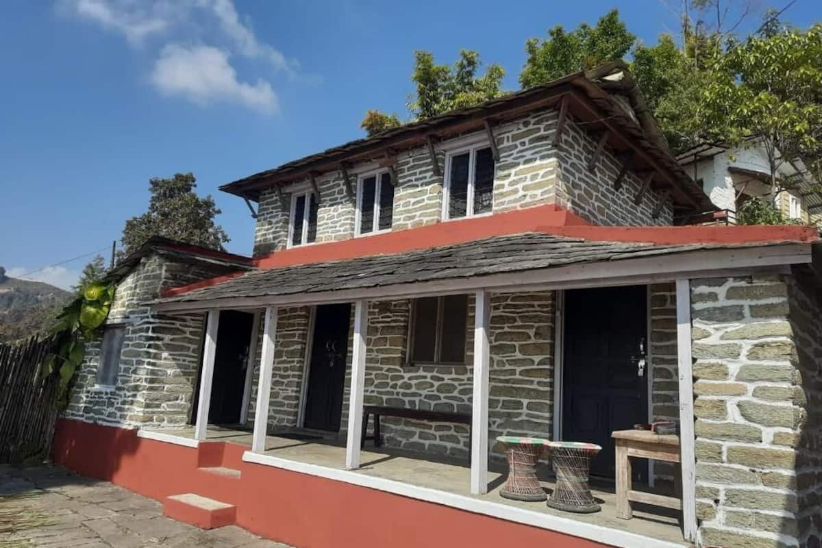 Ein Gebäude aus Stein mit rotem Dach, einer Veranda mit Bank und einem kleinen Tisch.