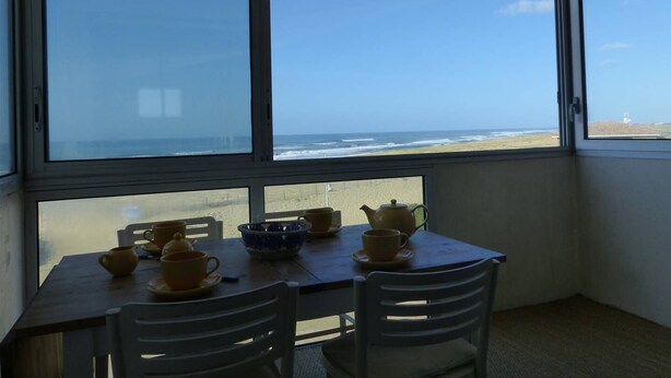 A room with a large window overlooking a beach. There is a table with cups and a teapot. - ATLANTES residence. Flat for 4 persons with ocean view (SOORTS HOSSEGOR)