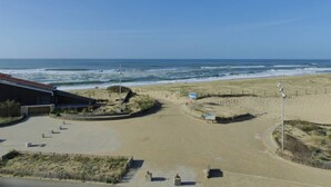 A beach view with a building, sandy beach, and ocean waves. - ATLANTES residence. Flat for 4 persons with ocean view (SOORTS HOSSEGOR)