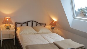 Ein Schlafzimmer mit einem Bett, zwei Nachttischlampen, einem Fenster und Blick ins Freie.