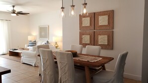 A dining area with a wooden table, white chairs, and pendant lights.