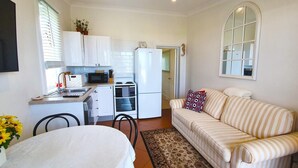 Un espacio habitable compacto con kitchenette, zona de comedor y sofá.