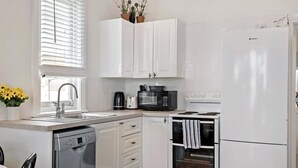 Una cocina moderna con armarios blancos, un lavavajillas Bosch, un microondas, una cafetera y un refrigerador.