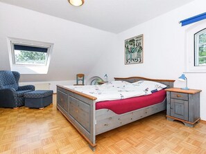 A bedroom with a bed, dresser, chair, and a window with a view.