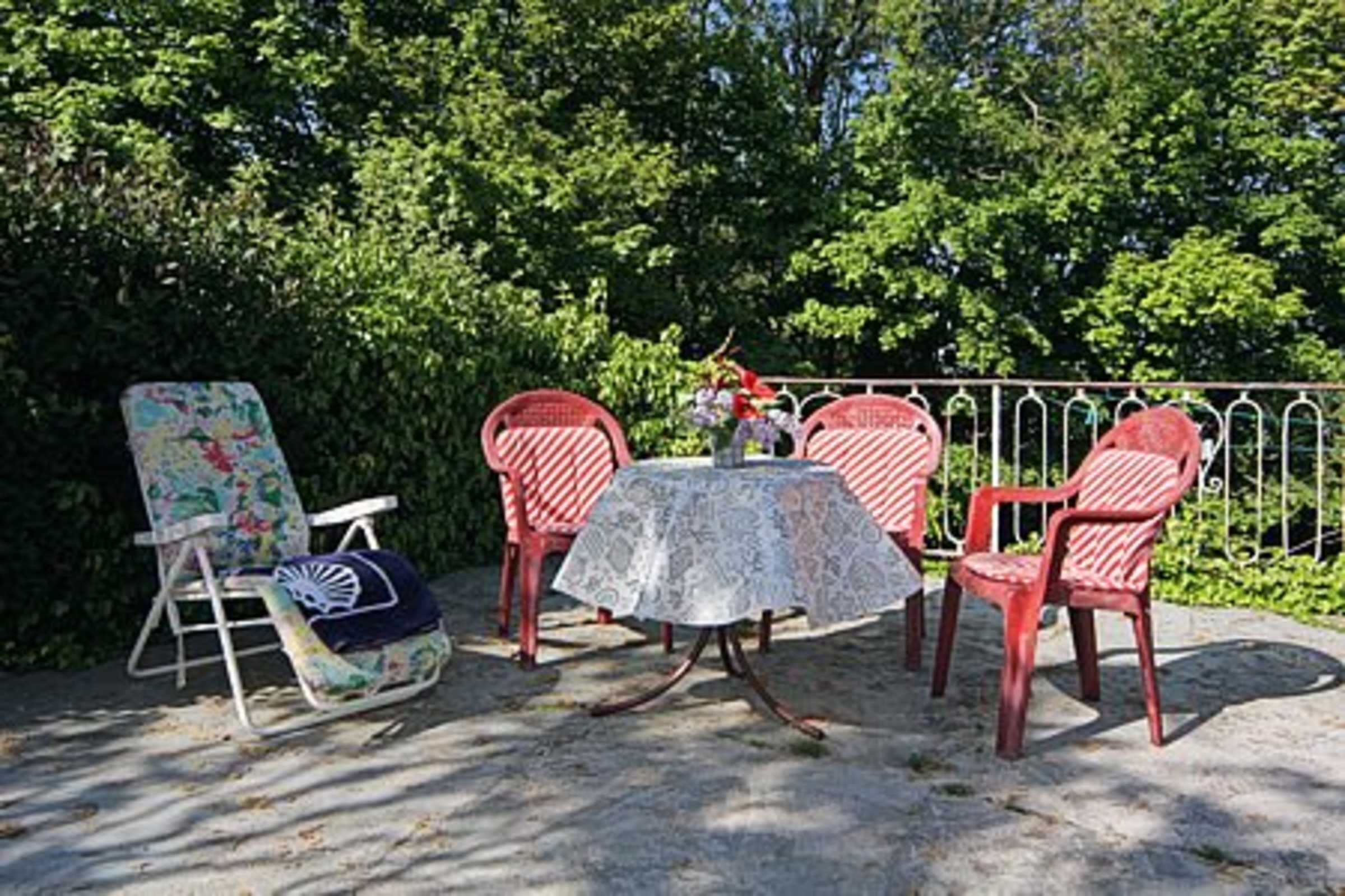 A patio with a table and chairs, surrounded by a metal fence and greenery.