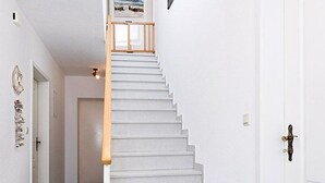 Una escalera blanca con barandilla de madera que lleva a una plataforma.
