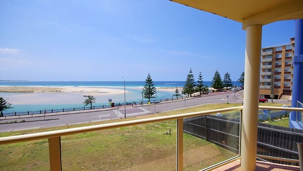Un balcone con vista su una spiaggia, una strada e un edificio sullo sfondo.