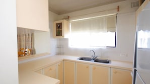 Una cucina con lavello, mobili, una finestra con tenda e frigorifero.