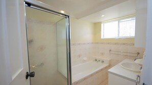 Un bagno con doccia in vetro, una vasca, un lavabo e una finestra con tende.