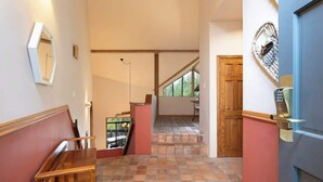 Un pasillo con un banco de madera, un tapete estampado y una puerta azul con un adorno decorativo.