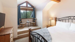 Un dormitorio con una cama, un escritorio, una silla, una mesita y una ventana con cortinas.