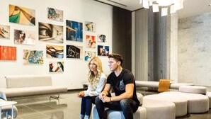 A modern lobby with abstract art on the walls, a seating area with a sofa and ottoman, and a tiled floor. - Gorgeous modern apartment in the heart of Miami (Miami)