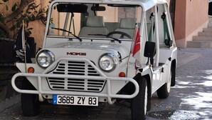 A white Moke vehicle parked on a cobblestone street.