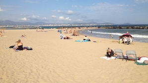 A beach with people sunbathing and swimming.