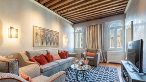 Una sala de estar con sofá, sillones, una mesa de centro y televisión.