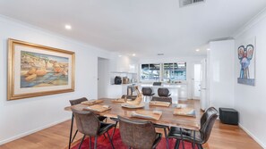 A modern dining area with a wooden table, leather chairs, and a painting on the wall.