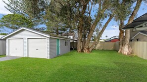 A residential property with a garage, a fenced yard, and mature trees.