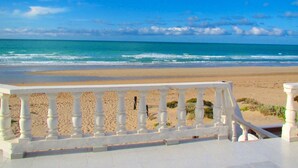 Vista da praia com um parapeito branco em primeiro plano.