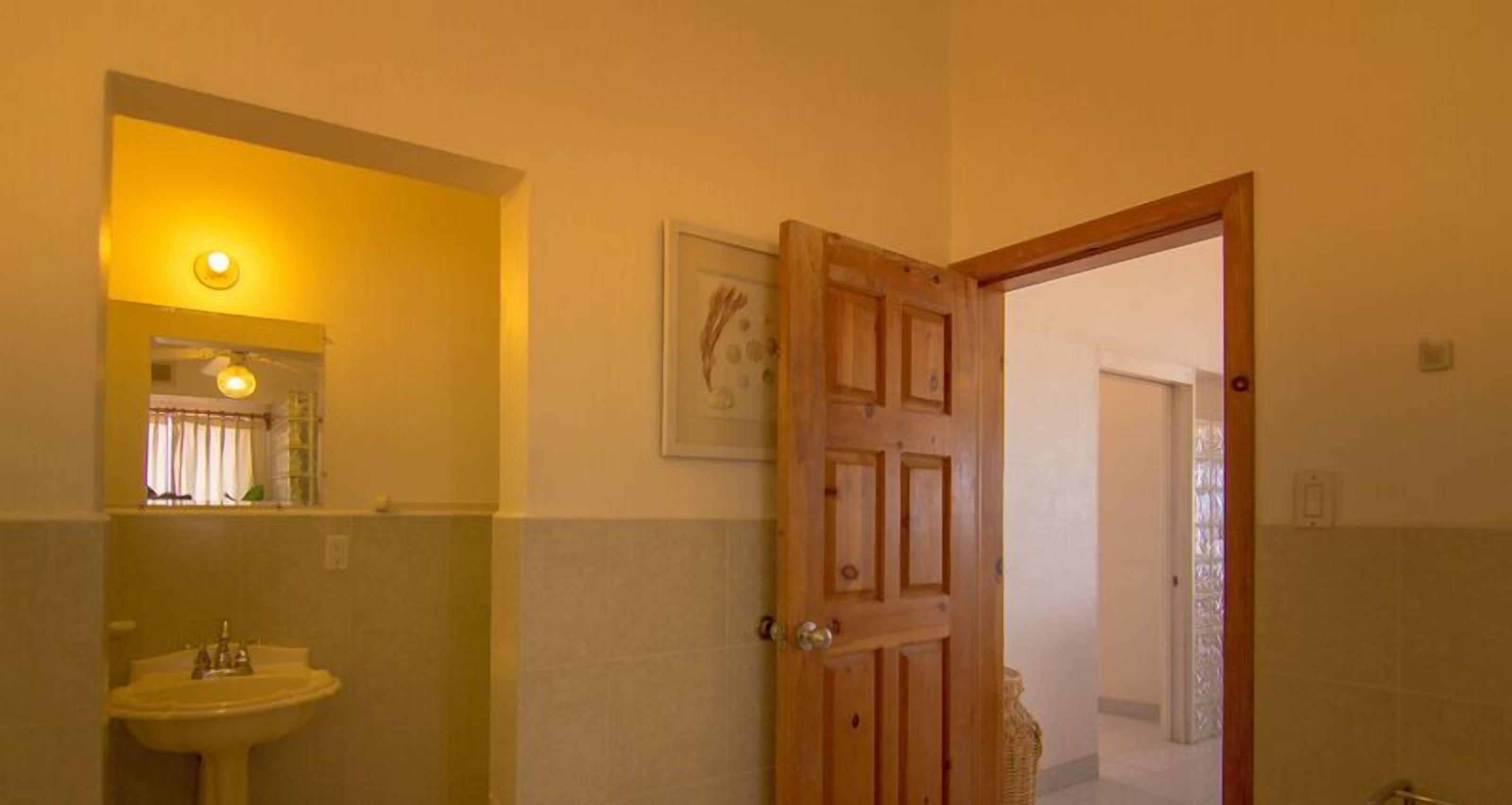 A bathroom with a sink, a wooden door, and a framed picture on the wall.