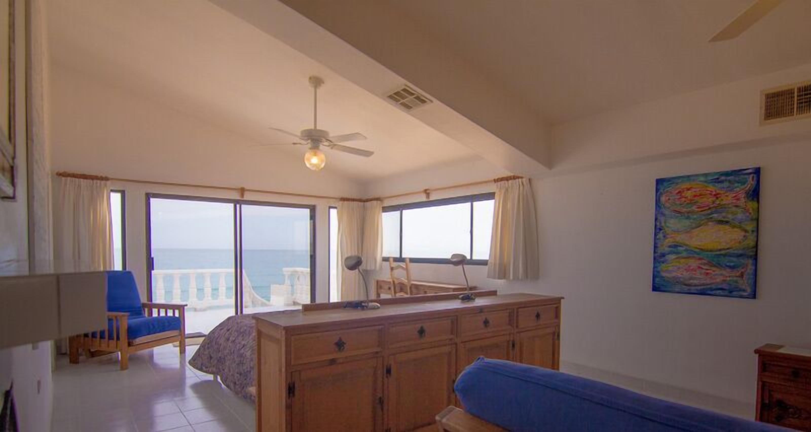 Ein Zimmer mit einem großen Holzschrank, einem blauen Sofa, einem Deckenventilator und einem Bild an der Wand.