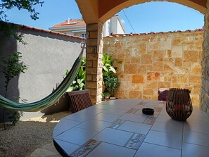 A patio with a round table, a hammock, and potted plants.