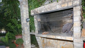 An outdoor stone barbecue area with a built-in grill, surrounded by potted plants. -  Studio apartment for two persons (Biograd na Moru)