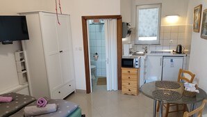 A compact hotel room with a bed, a small kitchenette, a dining area, and a TV. -  Studio apartment for two persons (Biograd na Moru)