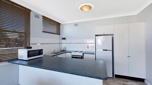 A modern kitchen with a microwave, stove, and refrigerator. - Golden Sands Apartment 10 (Blue Bay)