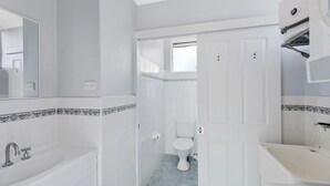A bathroom with a bathtub, toilet, and sink. - Golden Sands Apartment 10 (Blue Bay)