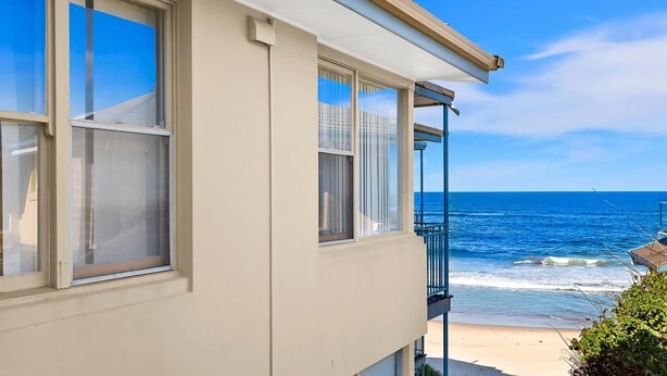 A coastal building with large windows overlooking the ocean, a balcony, and a clear view of the sea. - Golden Sands Apartment 10 (Blue Bay)