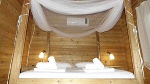 A wooden cabin bedroom with a bed, two bedside lamps, and a mosquito net. - Sakin Vadi Winehouse (Marmaris)