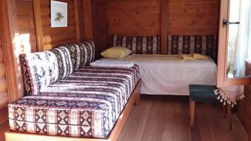 A cozy cabin-style room with a bed, a sofa, and a small table.
