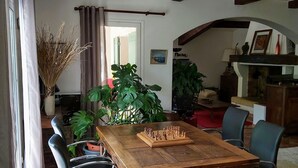 Ein Essbereich mit einem Holztisch, der für eine Mahlzeit gedeckt ist, umgeben von Stühlen, und einem Schachbrett auf dem Tisch.