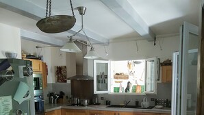 Eine Küche mit Holzausstattung, einem Esstisch mit Stühlen, einem Kühlschrank und einem Fenster mit Ausblick.