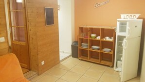 Uma cozinha compacta com um armário de madeira, uma geladeira branca e piso revestido de azulejos.