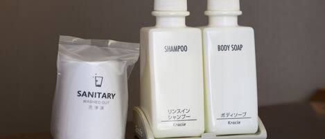 Two white bottles labeled 'SHAMPOO' and 'BODY SOAP' with pumps, and a white bag labeled 'SANITARY WASHED OUT'.