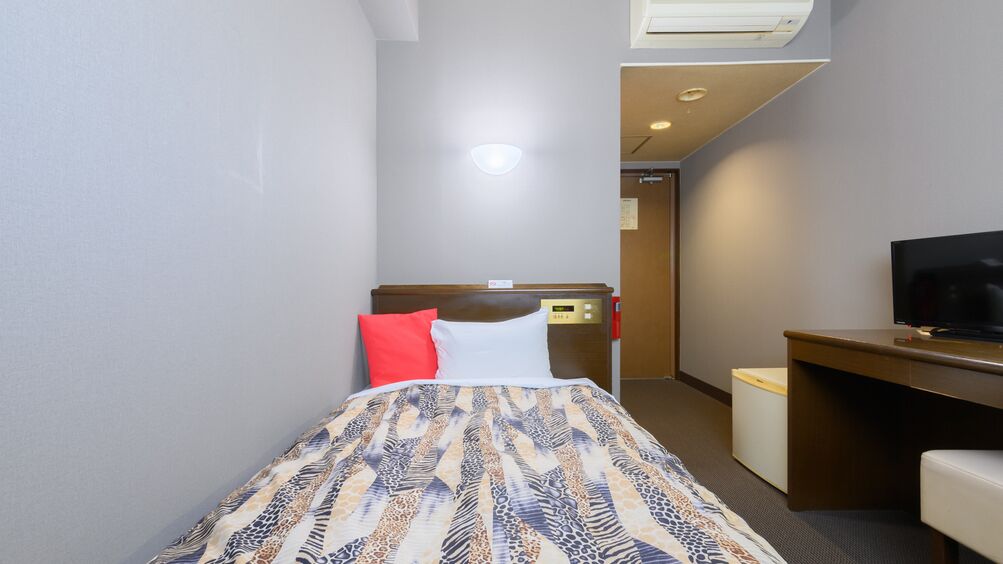 Une chambre d’hôtel équipée d’un lit, d’un bureau, d’une télévision et d’un appareil de climatisation.