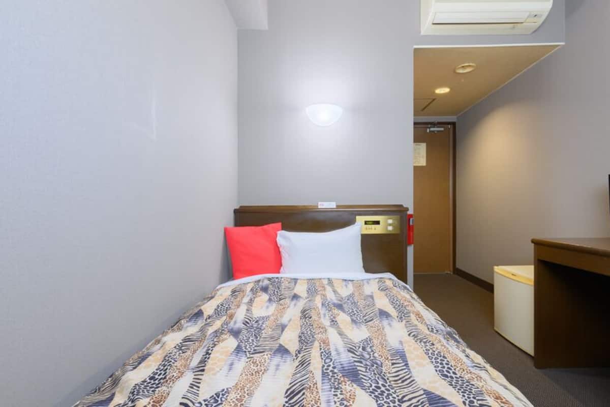 Una habitación de hotel con una cama, un escritorio, un televisor y un equipo de aire acondicionado.