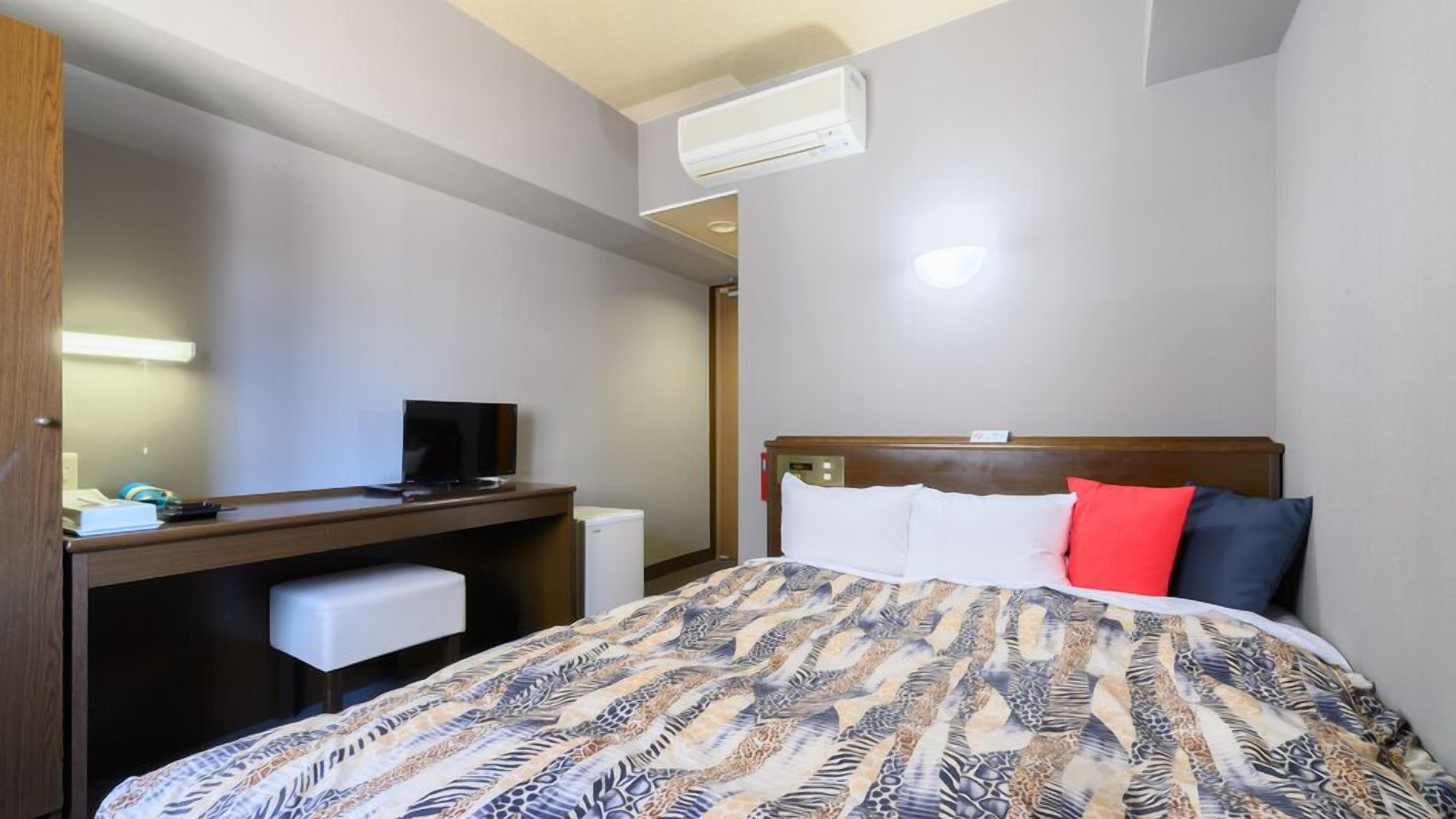 Une chambre d’hôtel équipée d’un lit, d’un bureau, d’une télévision et d’un appareil de climatisation.