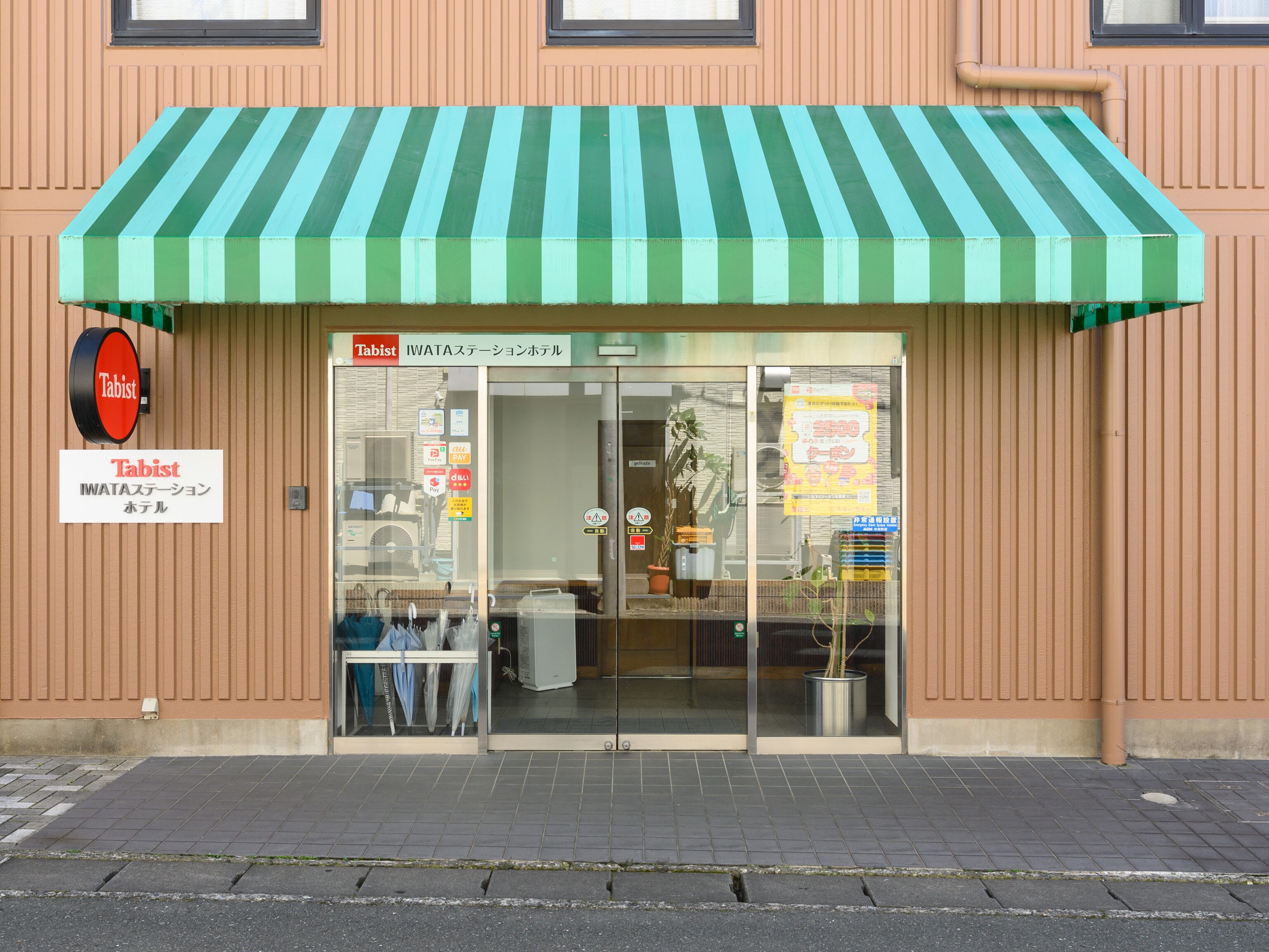 Ein Schaufenster mit einer grün gestreiften Markise, einem Schild mit der Aufschrift "Tabist" und einem Glastür-Eingang.