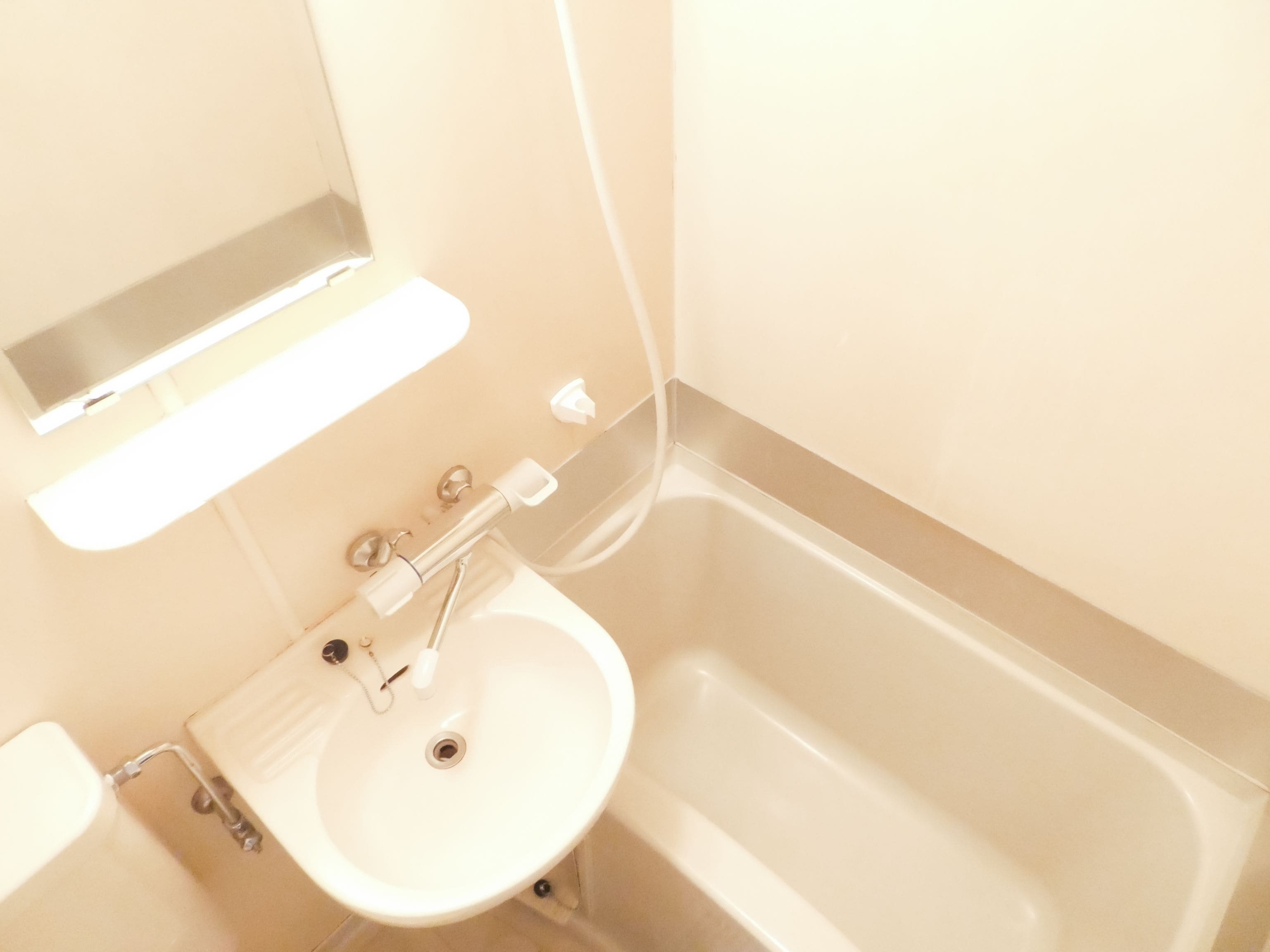 A bathroom with a white sink, a mirror above it, and a bathtub.