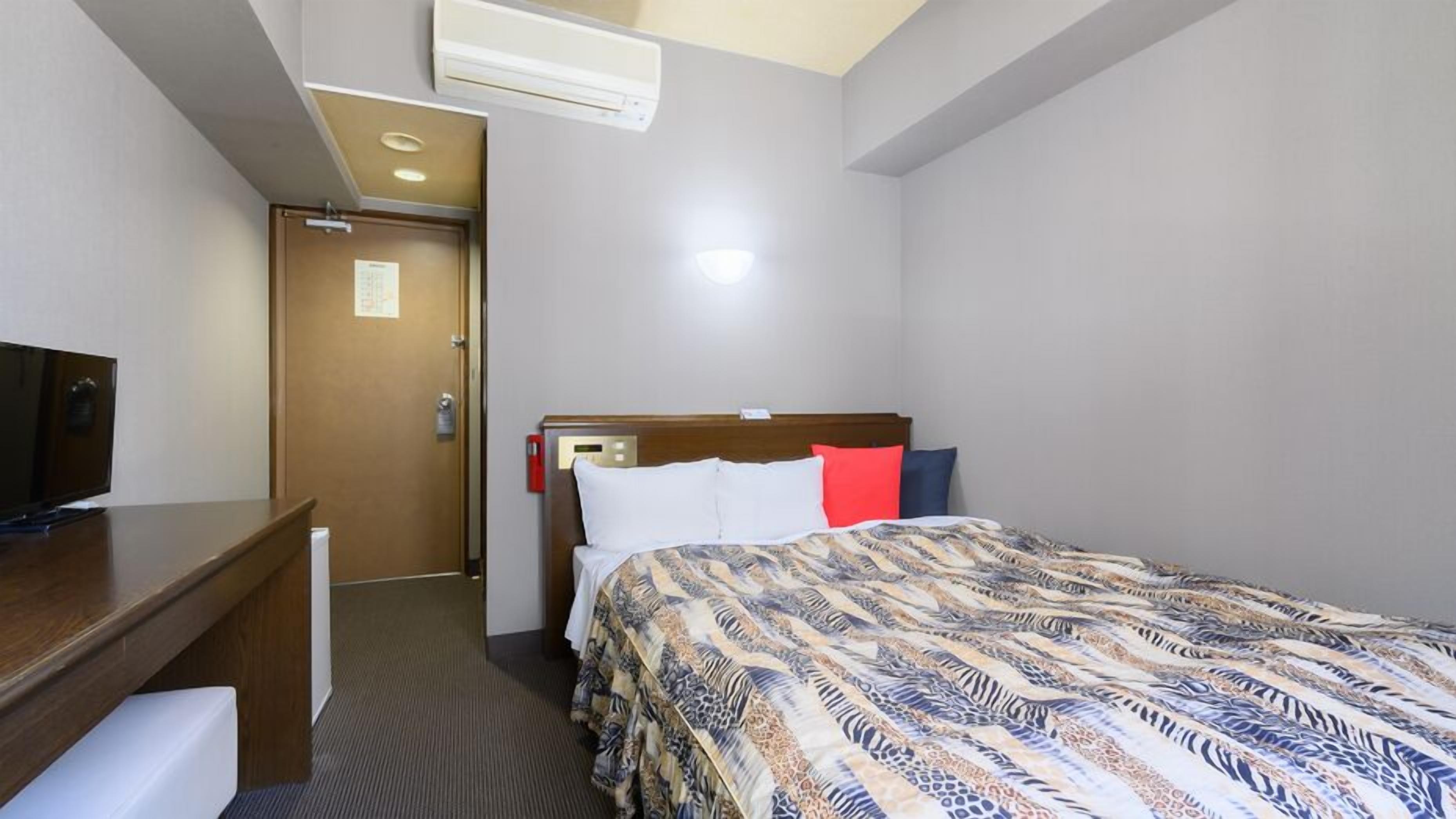Une chambre d’hôtel équipée d’un lit, d’un bureau, d’une télévision et d’un appareil de climatisation.