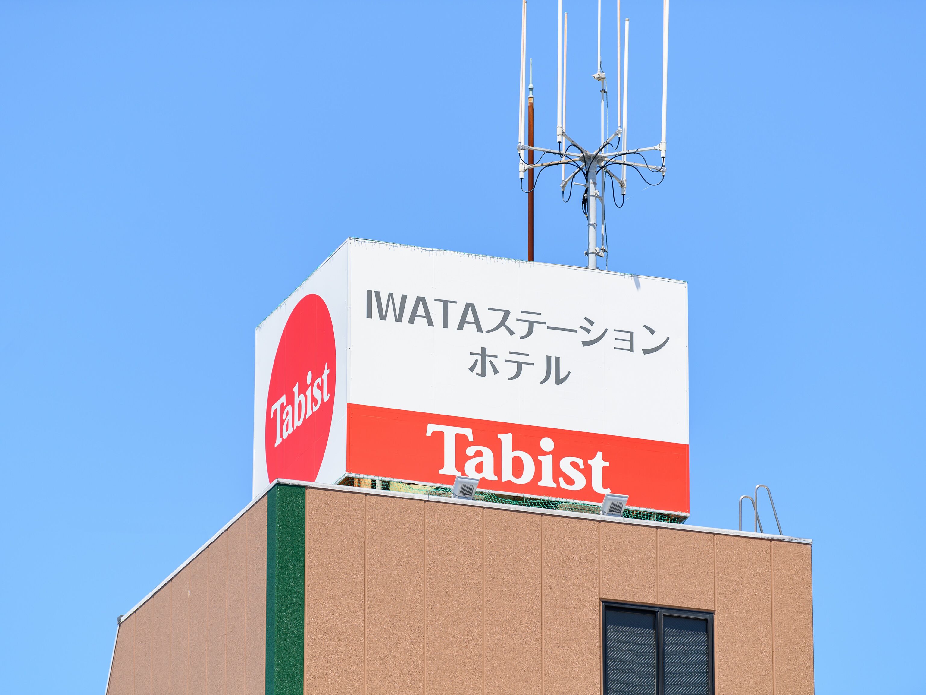 A building with a sign that reads "Tabist" and "WATAステーション ホテル" indicating it is a Tabist hotel with a WATA station.